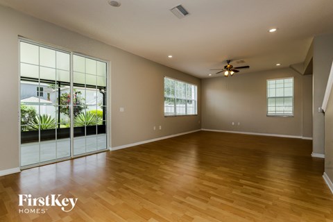 A spacious room with wooden floors and a ceiling fan.