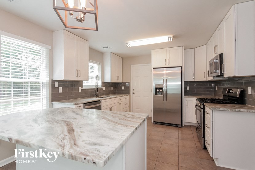 a large kitchen with white cabinets and a stainless steel refrigerator
