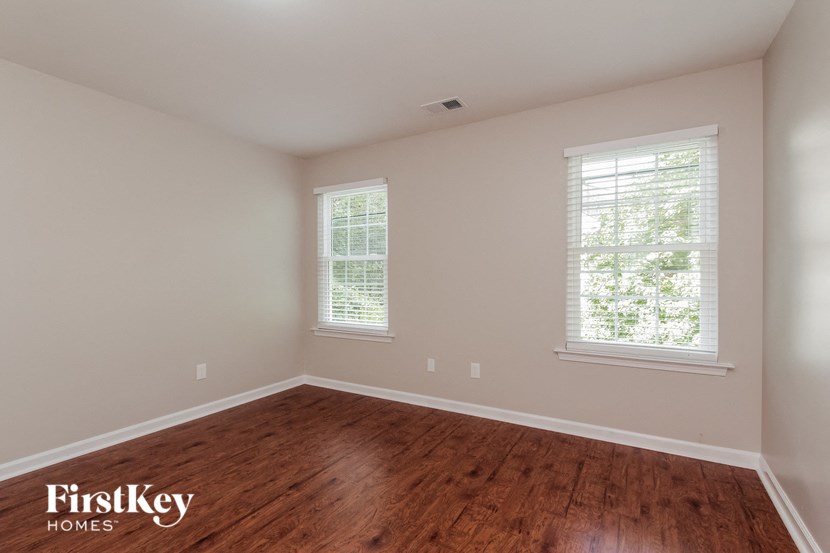 a bedroom with a wooden floor and two windows