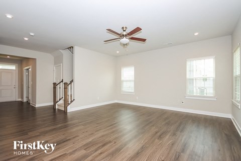 A spacious room with a ceiling fan and wooden flooring.