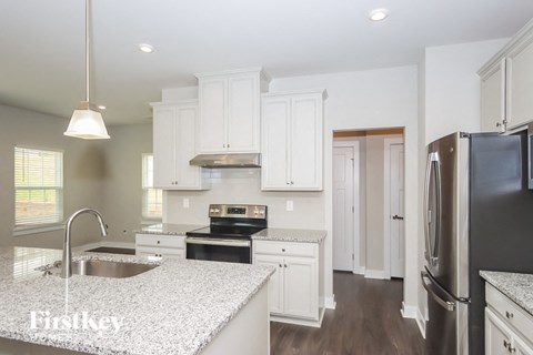 A kitchen with white cabinets and a black fridge.