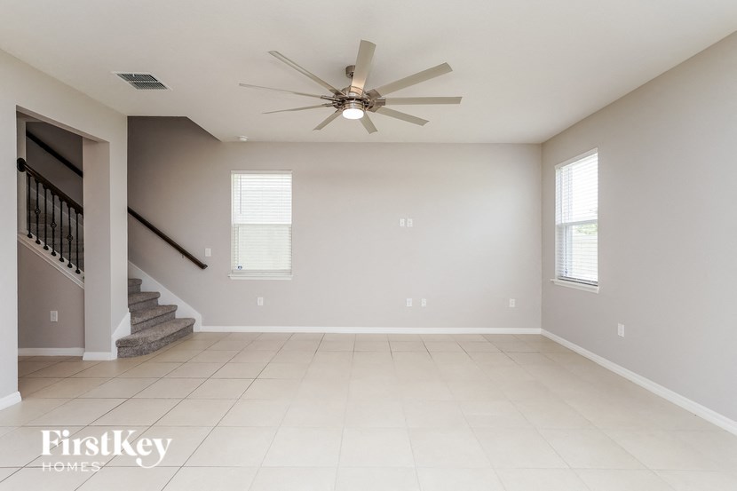 A spacious room with a staircase and a ceiling fan.