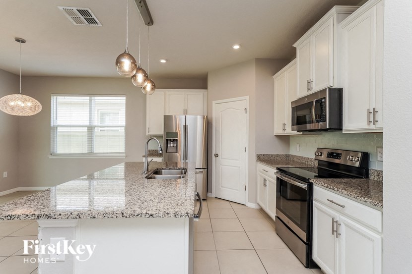 A kitchen with granite countertops and white cabinets.