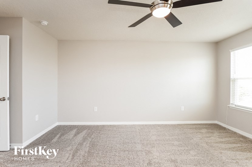 A room with a ceiling fan and a carpeted floor.