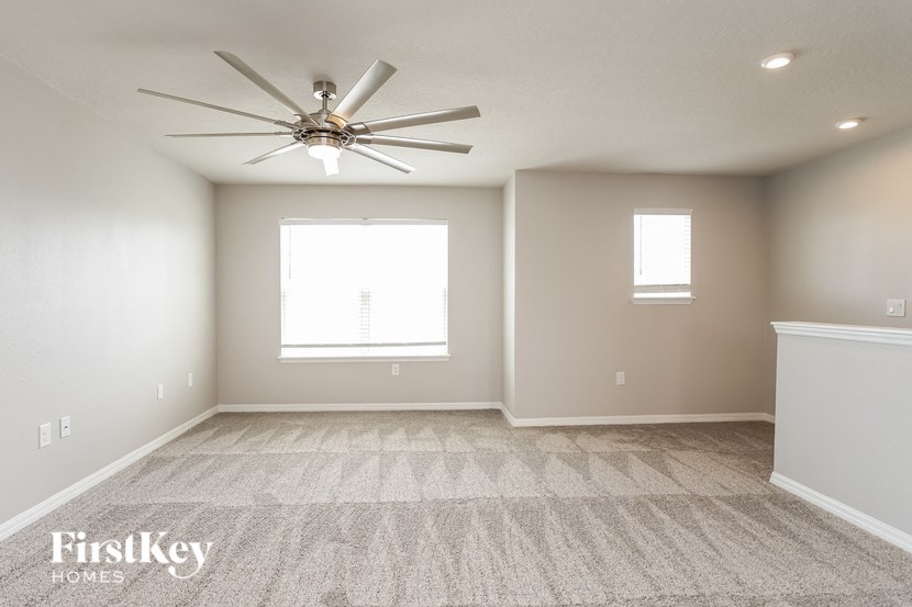A spacious room with a ceiling fan and carpeted floor.