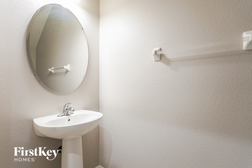 A white sink under a round mirror in a bathroom.