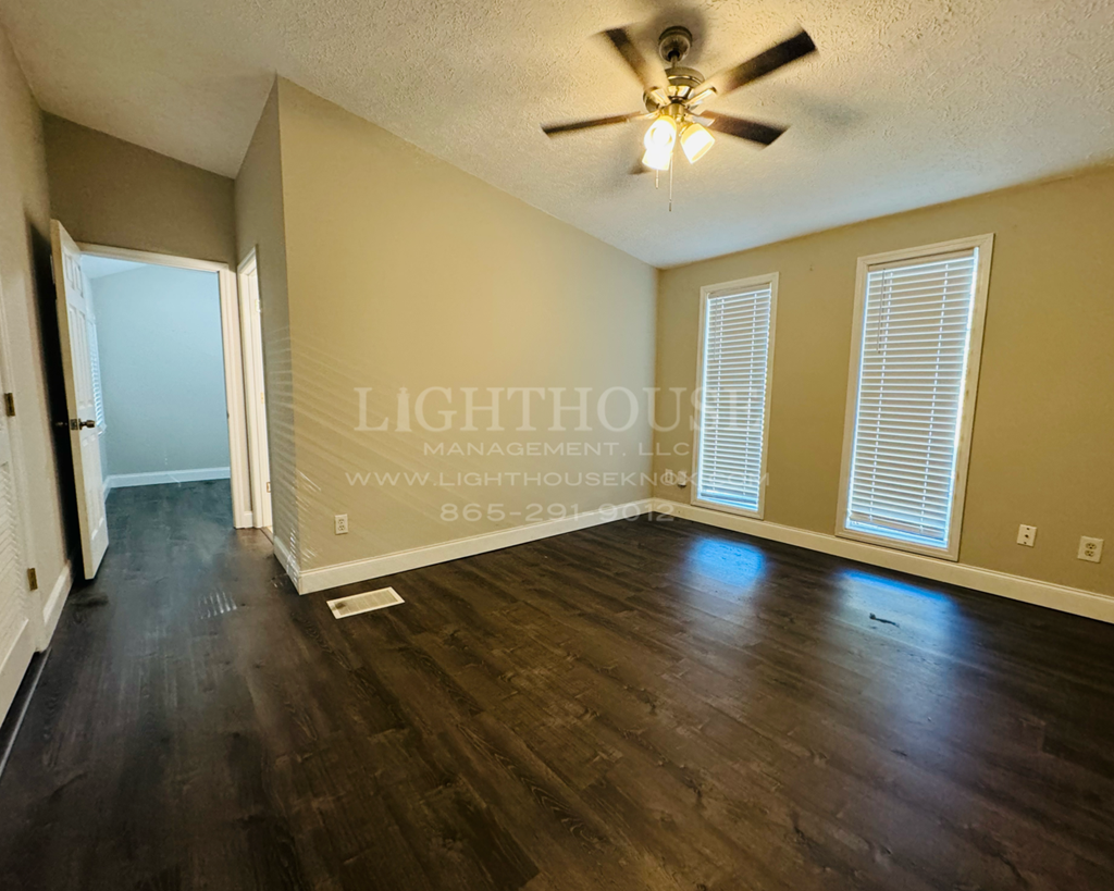 an empty living room with wood floors and a ceiling fan