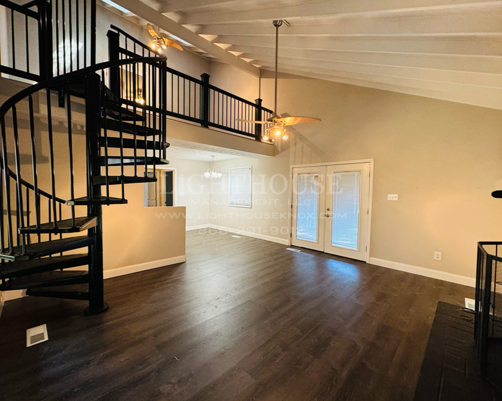 a living room with a spiral staircase and a door to a balcony