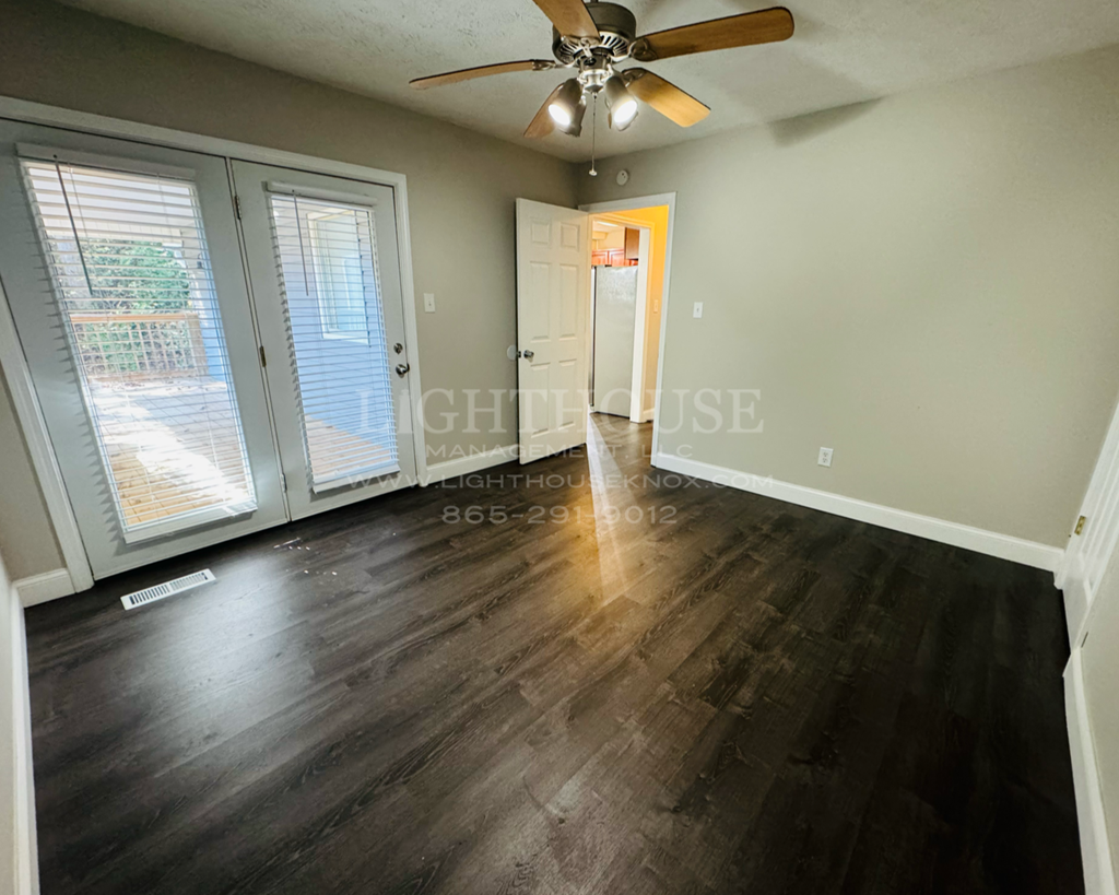 an empty living room with wood floors and a ceiling fan