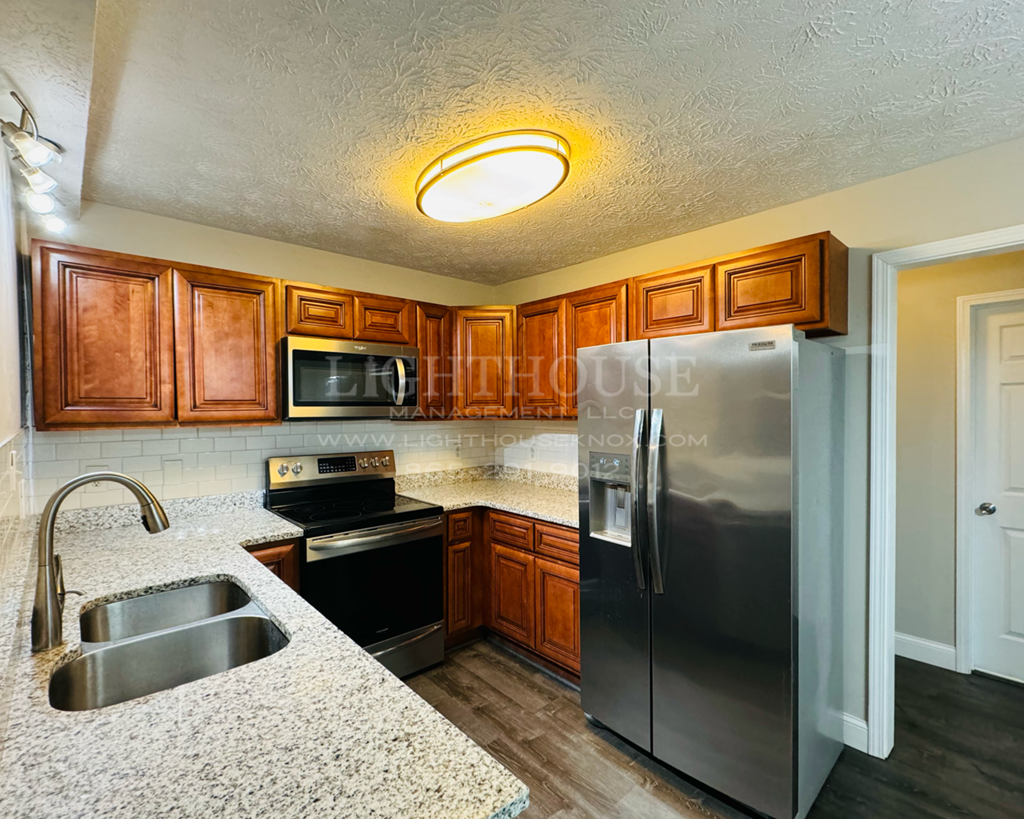 a kitchen with granite counter tops and a stainless steel refrigerator