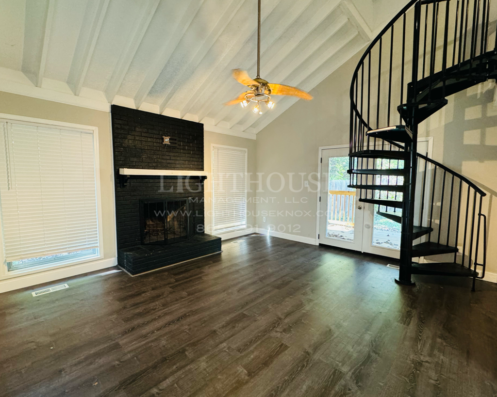 a living room with a fireplace and a spiral staircase