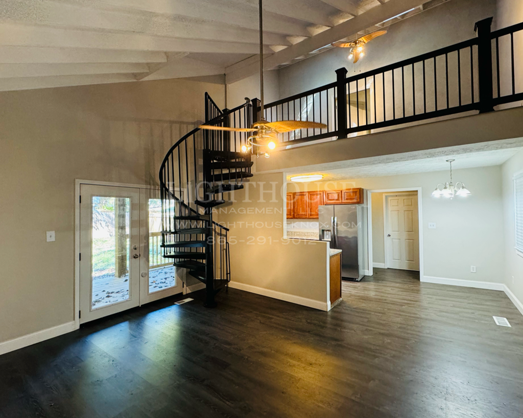 a spiral staircase in the middle of a living room with wood floors