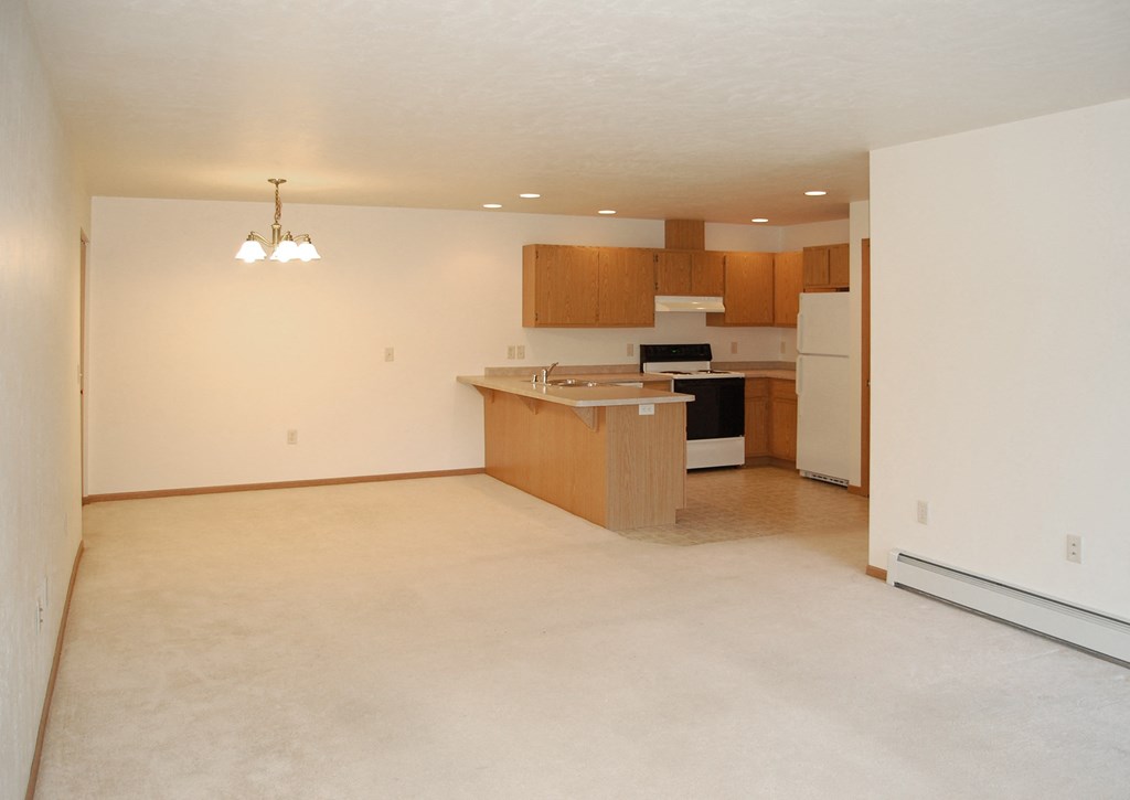 an empty living room with a kitchen in it