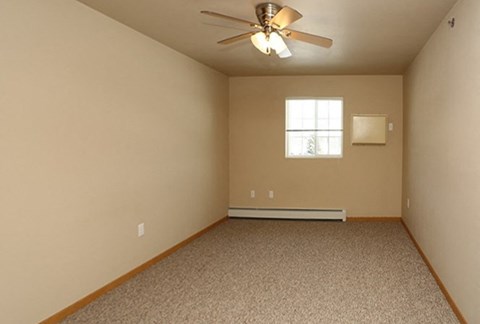 an empty room with a ceiling fan and a window