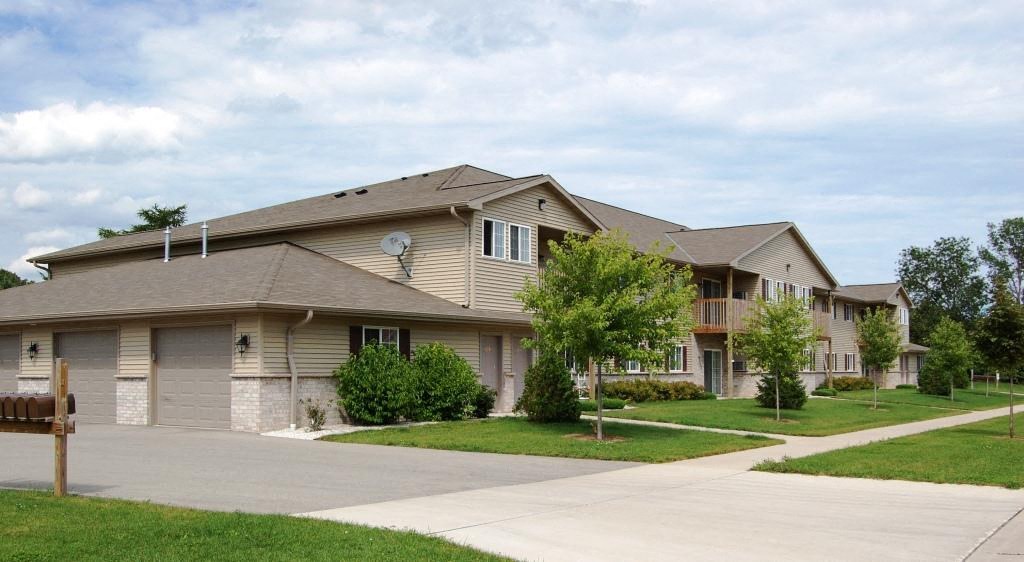 a beige house with a driveway and trees