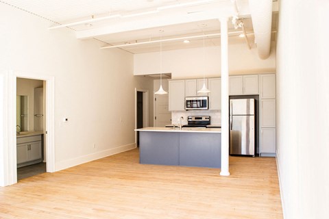 an empty kitchen with a blue island and white cabinets