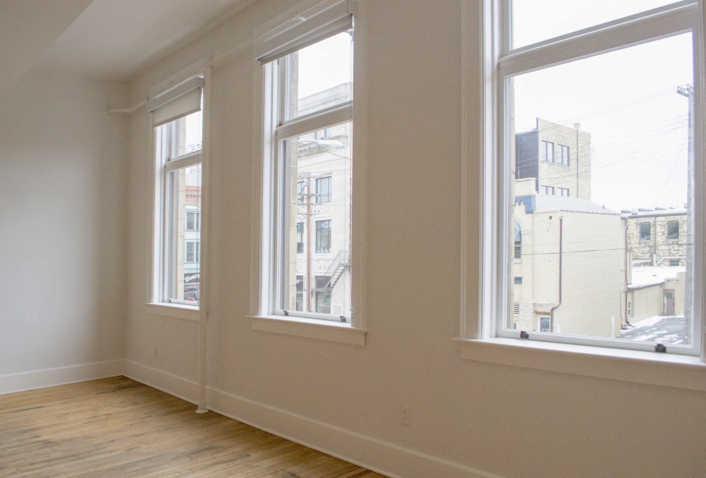 a living room with three windows and a wooden floor