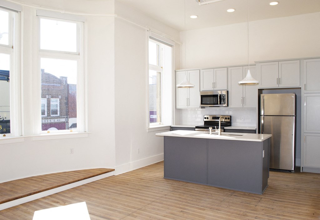 a kitchen with an island and stainless steel appliances and white cabinets