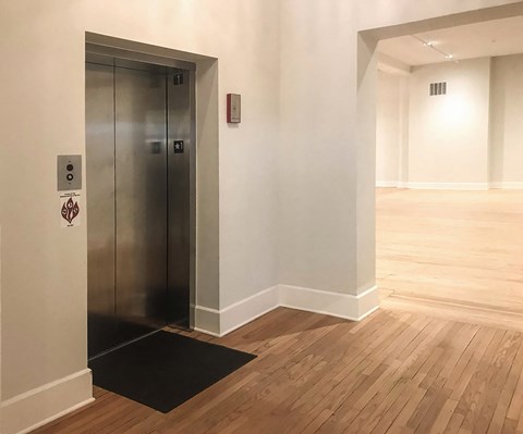 a large room with wooden floors and a metal elevator