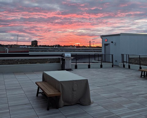 a rooftop terrace with a table and a sunset
