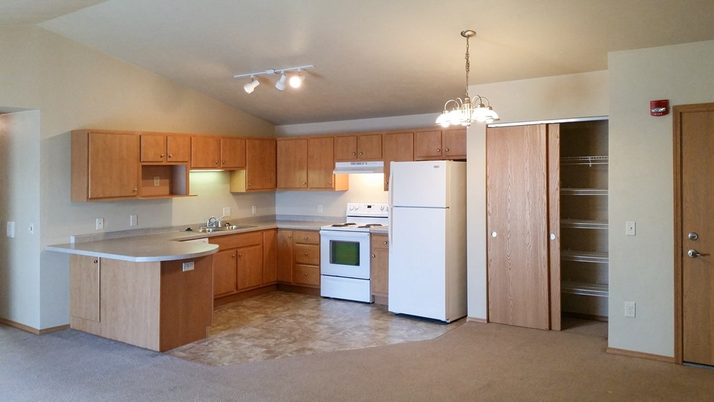 an empty kitchen with white appliances and wooden cabinets