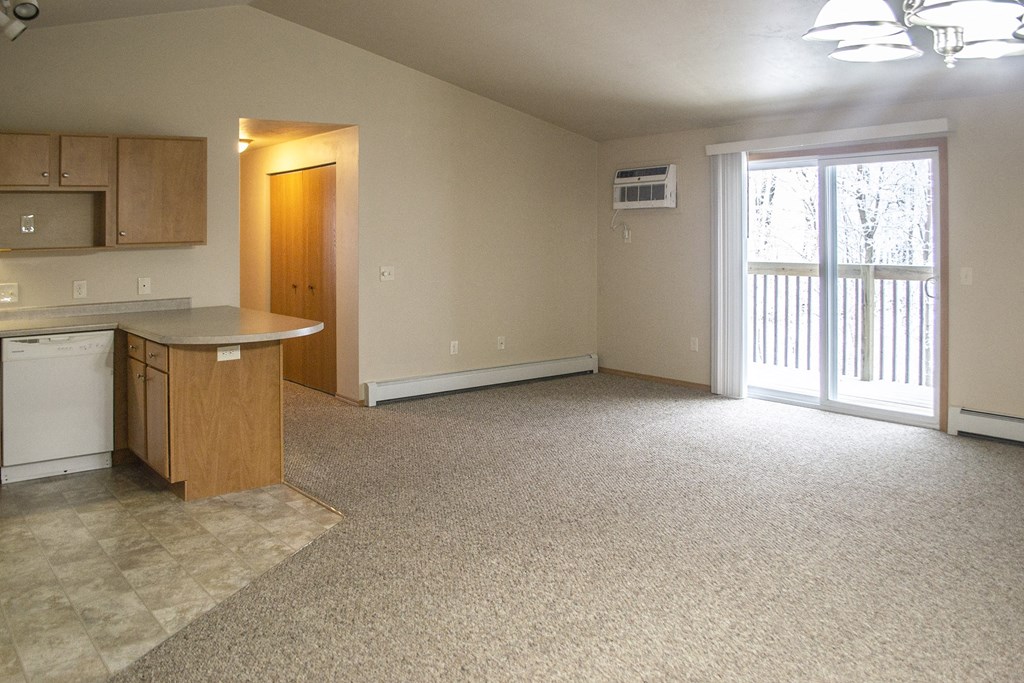 an empty kitchen and living room with a door to a balcony