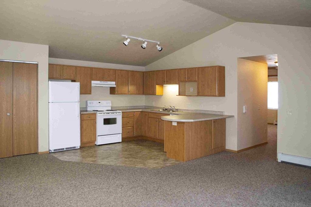 an empty kitchen with white appliances and wooden cabinets