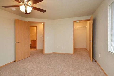 an empty bedroom with two doors and a ceiling fan