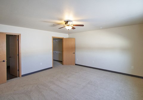 a empty living room with a ceiling fan and a closet