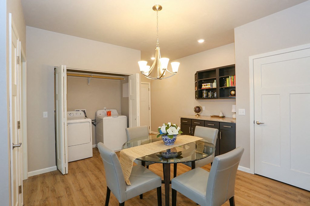 a dining room with a table and chairs and a kitchen with a refrigerator