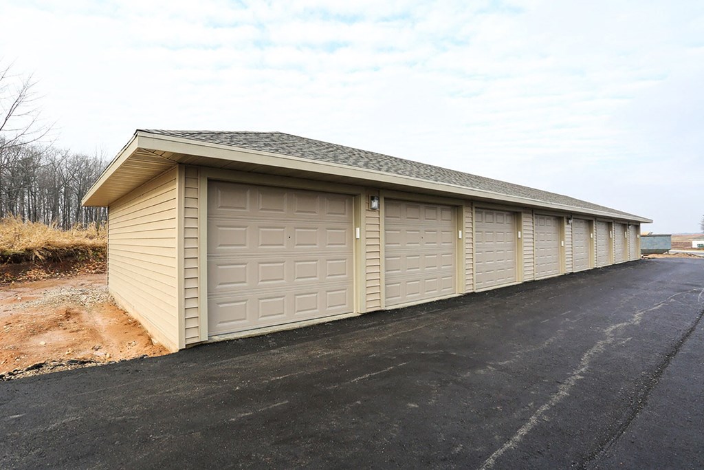 a small garage with white doors on the side of a road