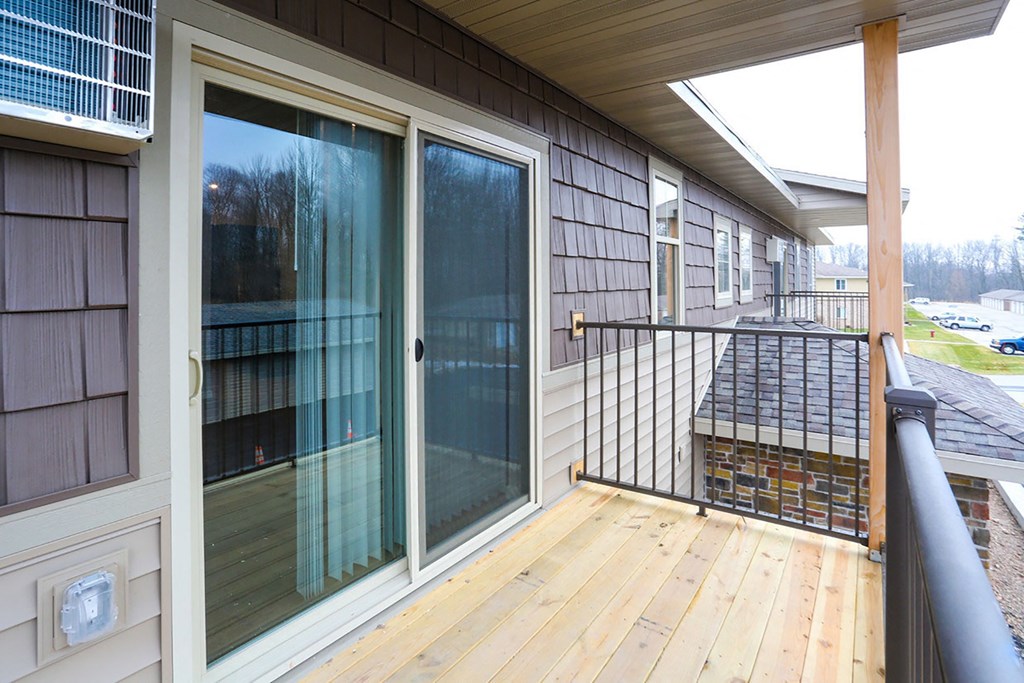 a covered porch with glass sliding doors and a railing