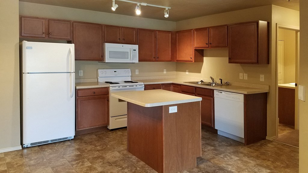 an empty kitchen with white appliances and wooden cabinets