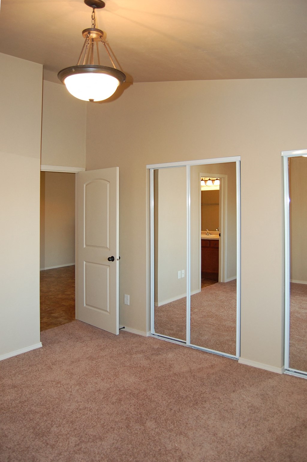 an empty living room with a mirror and a door to a bathroom
