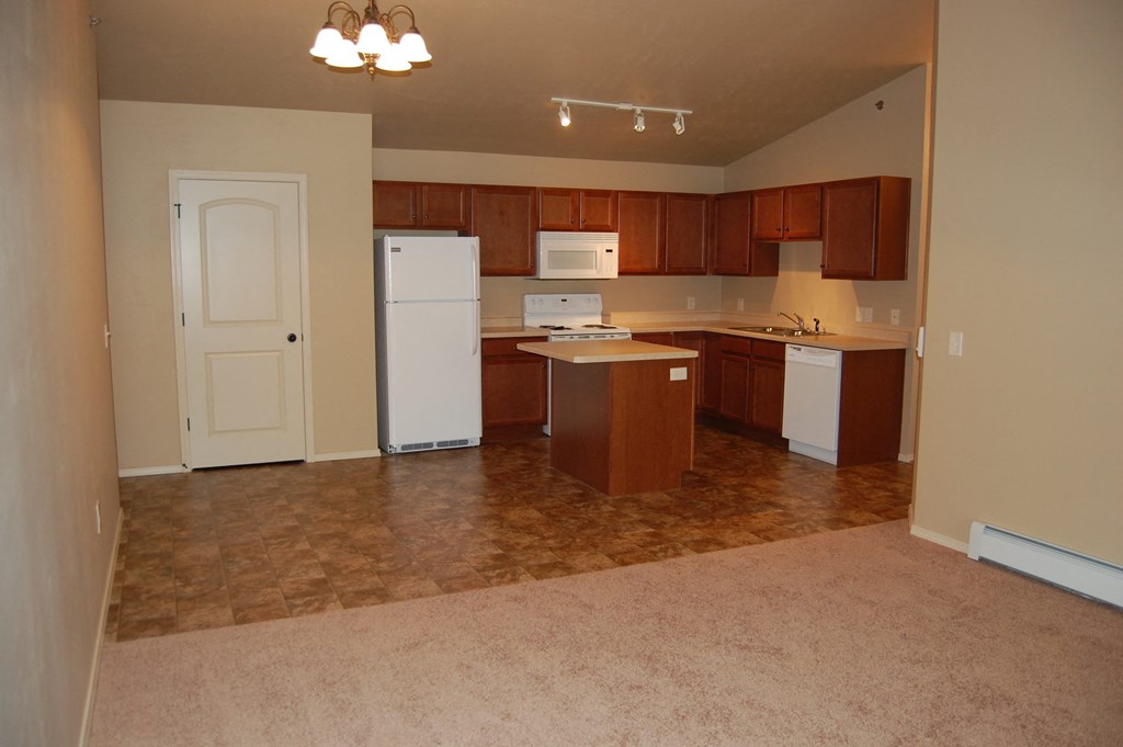 an empty kitchen with white appliances and wooden cabinets
