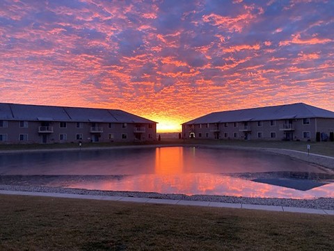 a sunset over a building reflected in a pool of water