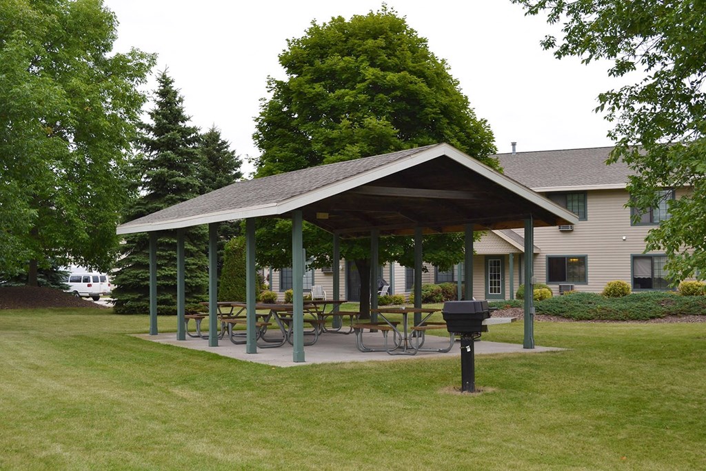 a pavilion with a picnic table in the yard of a house