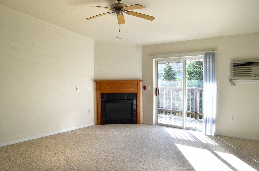 an empty living room with a fireplace and a ceiling fan