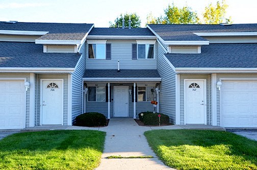 a blue house with white doors and a sidewalk