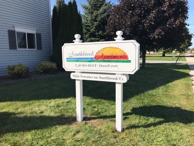 a sign in the grass in front of a house