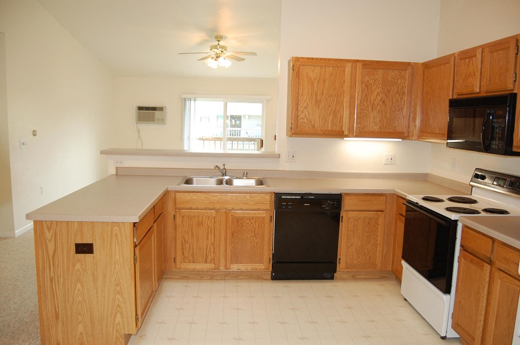 an empty kitchen with wooden cabinets and black appliances
