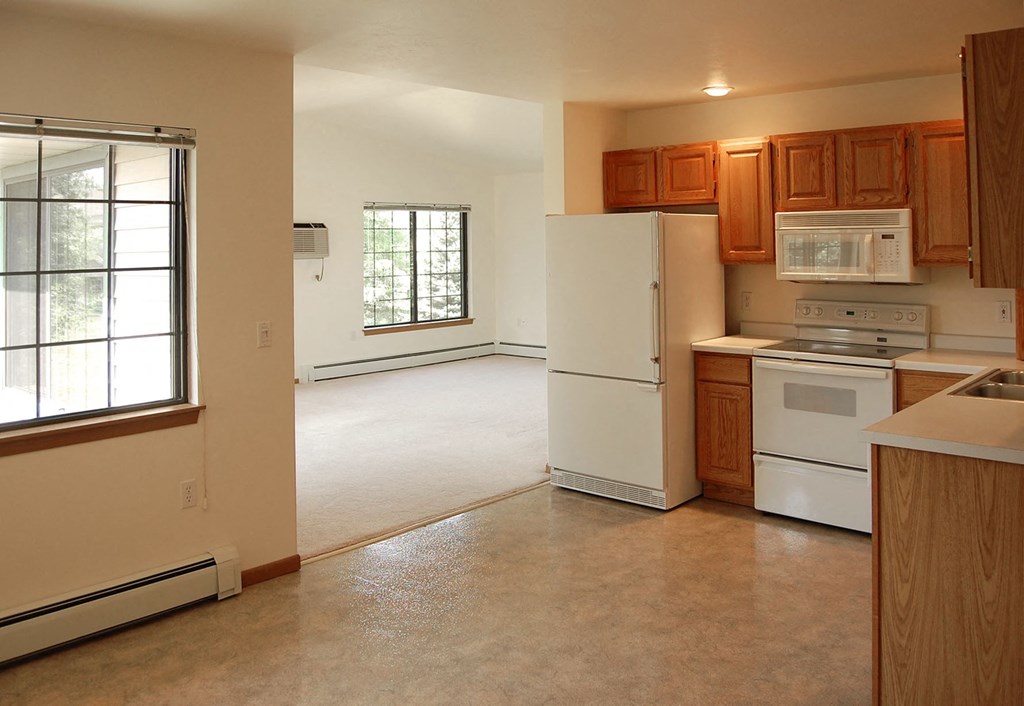 an empty kitchen with white appliances and wooden cabinets