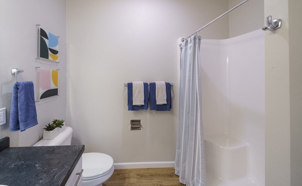a bathroom with a shower and a toilet and blue towels