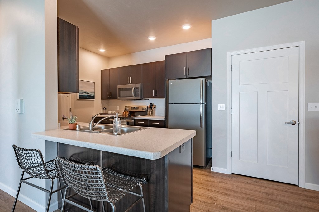 a kitchen with stainless steel appliances and a island with three bar stools
