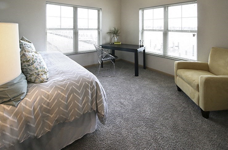 a bedroom with a bed and a desk and two windows