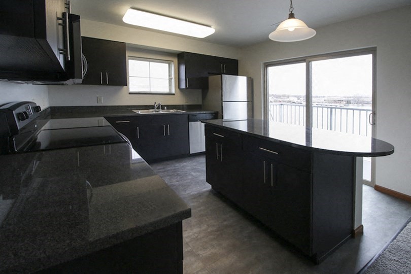 an empty kitchen with black cabinets and a window