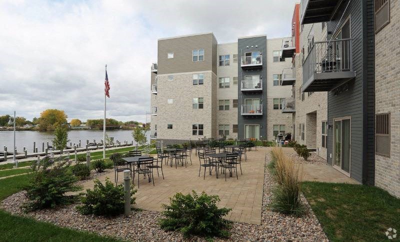 an apartment building with tables and chairs near the water