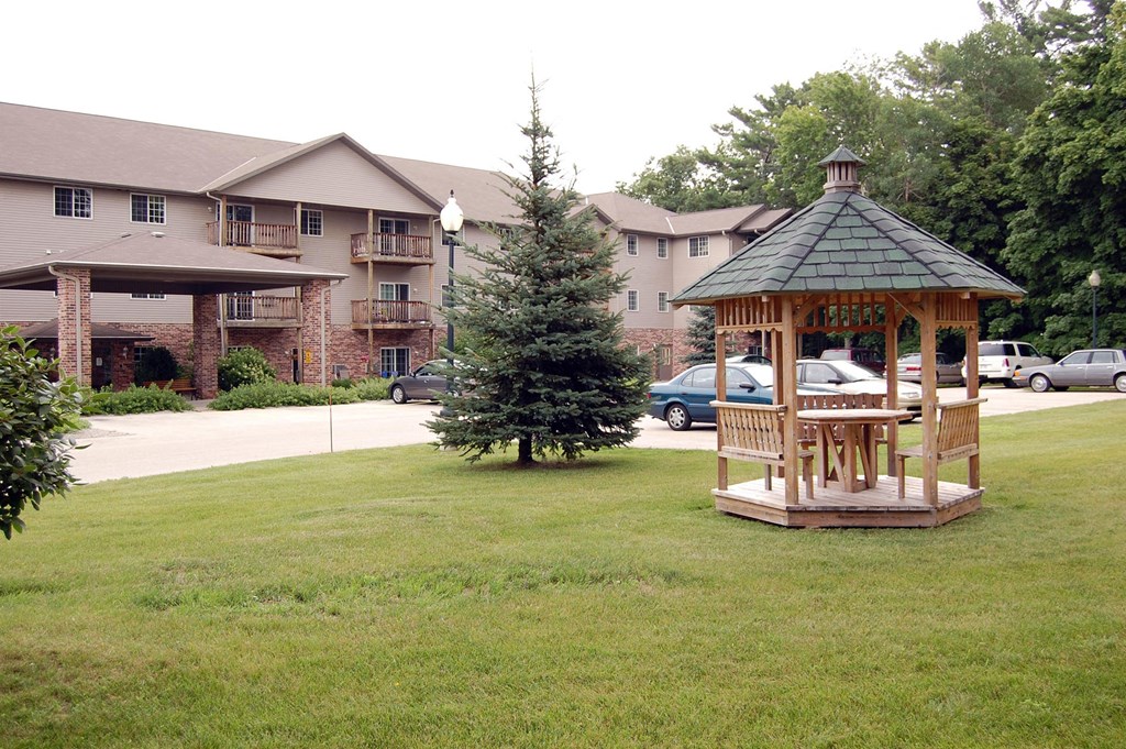 a gazebo in the middle of a yard with a building in the