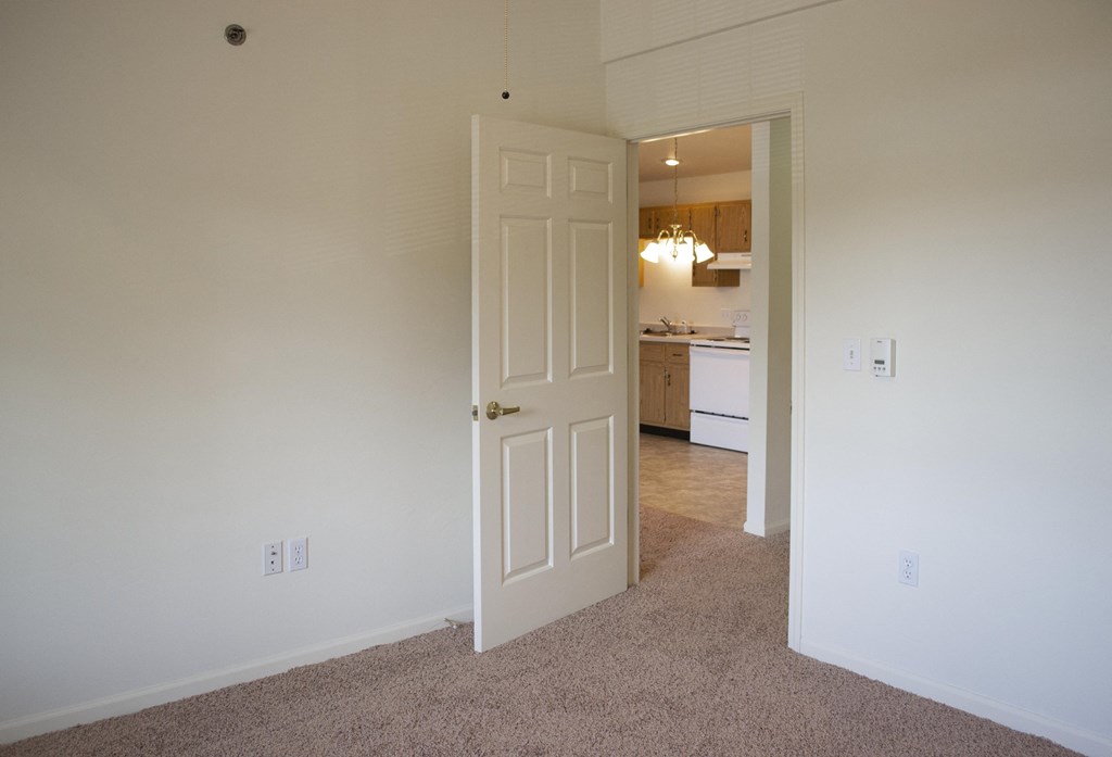 a bedroom with a door leading into a kitchen