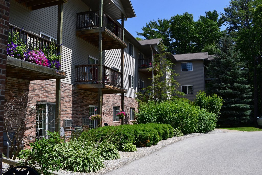 a street in front of an apartment building with flowers on the balconies